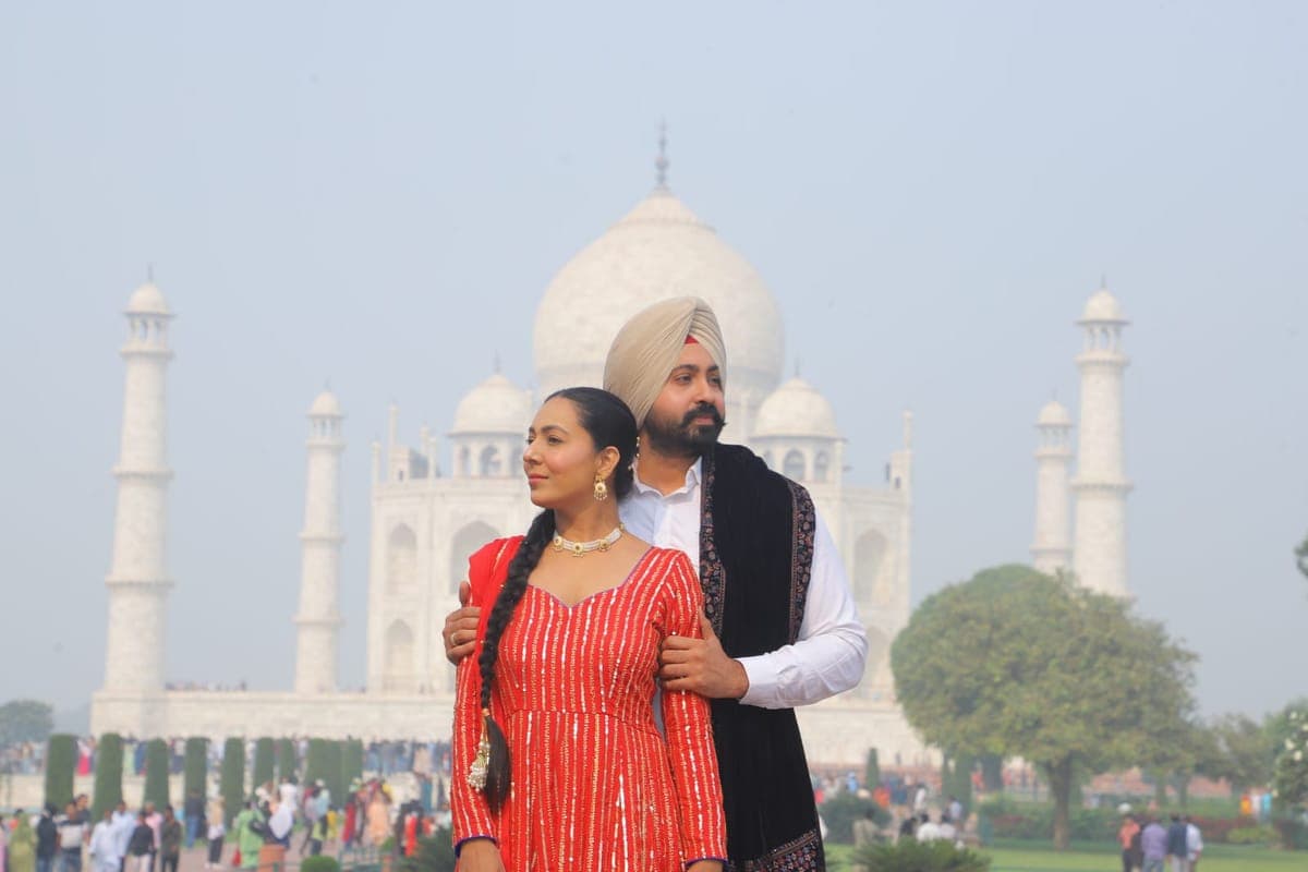 A couple in traditional dress photographed in front of the Taj Mahal