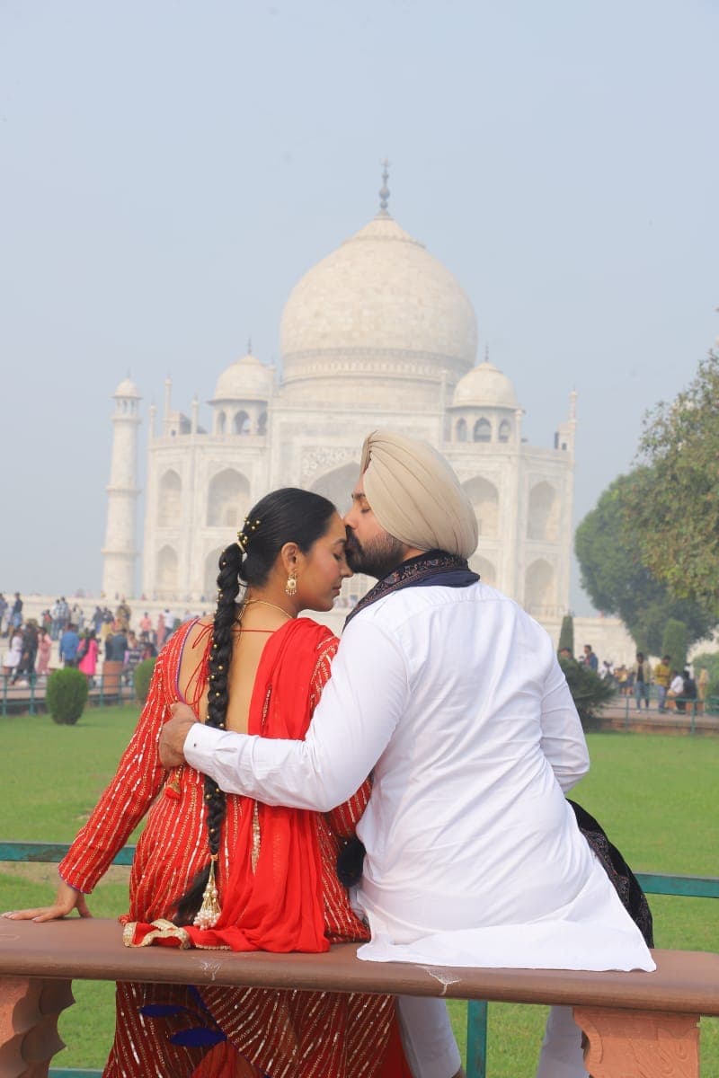 A couple sharing a moment on a bench with the Taj Mahal behind