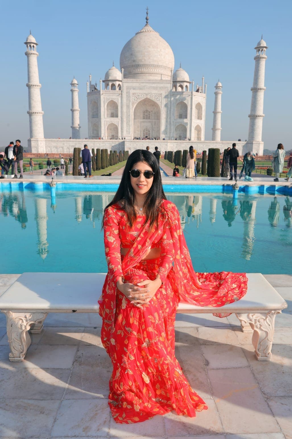 A guest in a red saree beside the reflecting pool at the Taj Mahal