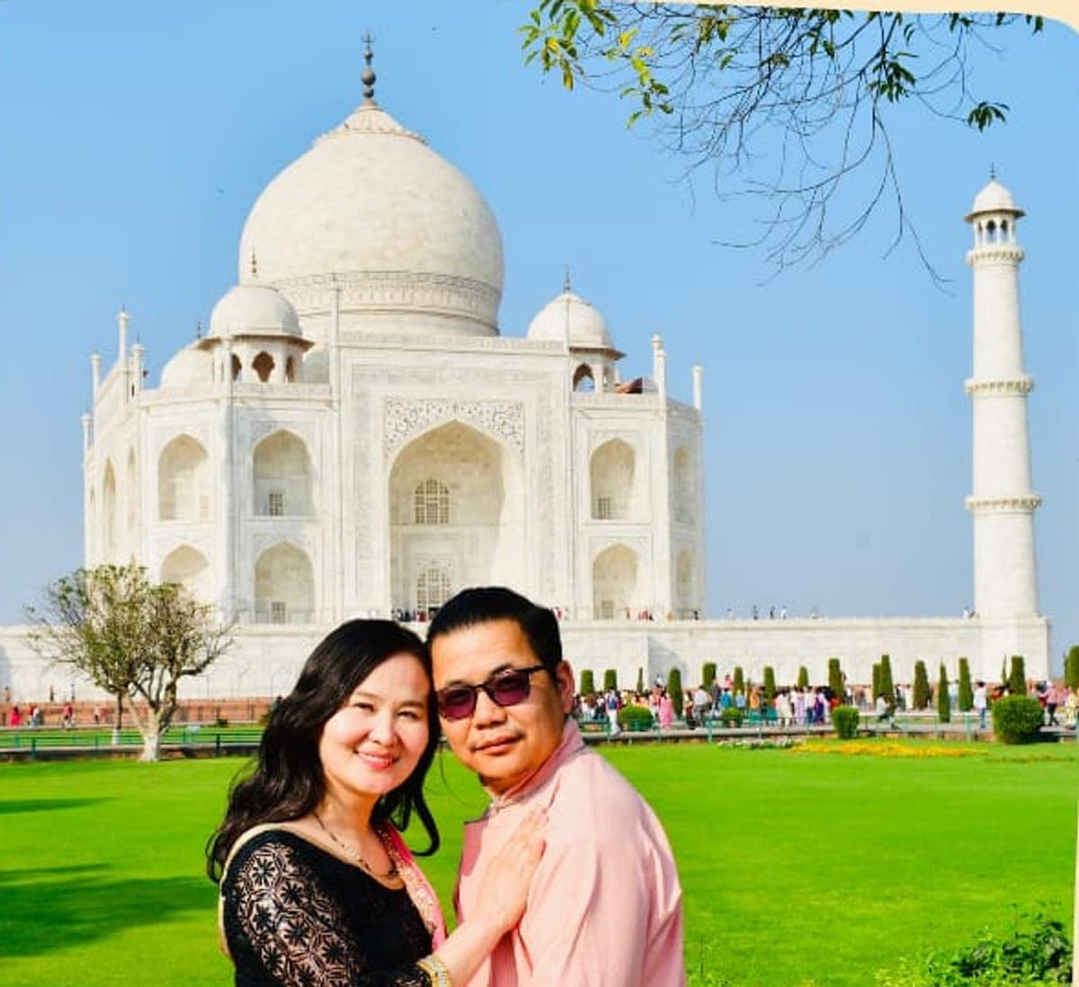 A couple photographed on the lawns with the Taj Mahal behind them